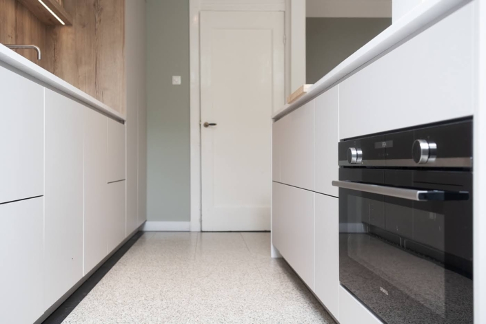 Lichte maatwerkkeuken met ge&iuml;ntegreerde oven en strakke greeplijsten
